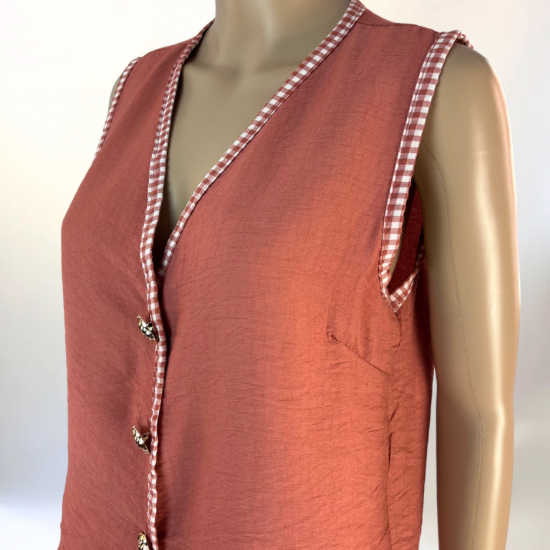 La imagen muestra un conjunto de dos piezas en color verde, compuesto por un chaleco sin mangas con botones decorativos en la parte frontal y una falda larga con abertura lateral. El diseño es elegante y versátil, ideal para ocasiones casuales o semi-formales. El tejido ligero y transpirable garantiza comodidad y un ajuste favorecedor.