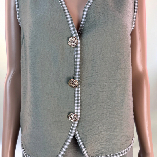 La imagen muestra un conjunto de dos piezas en color verde, compuesto por un chaleco sin mangas con botones decorativos en la parte frontal y una falda larga con abertura lateral. El diseño es elegante y versátil, ideal para ocasiones casuales o semi-formales. El tejido ligero y transpirable garantiza comodidad y un ajuste favorecedor.