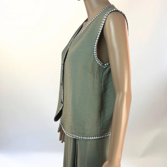 La imagen muestra un conjunto de dos piezas en color verde, compuesto por un chaleco sin mangas con botones decorativos en la parte frontal y una falda larga con abertura lateral. El diseño es elegante y versátil, ideal para ocasiones casuales o semi-formales. El tejido ligero y transpirable garantiza comodidad y un ajuste favorecedor.